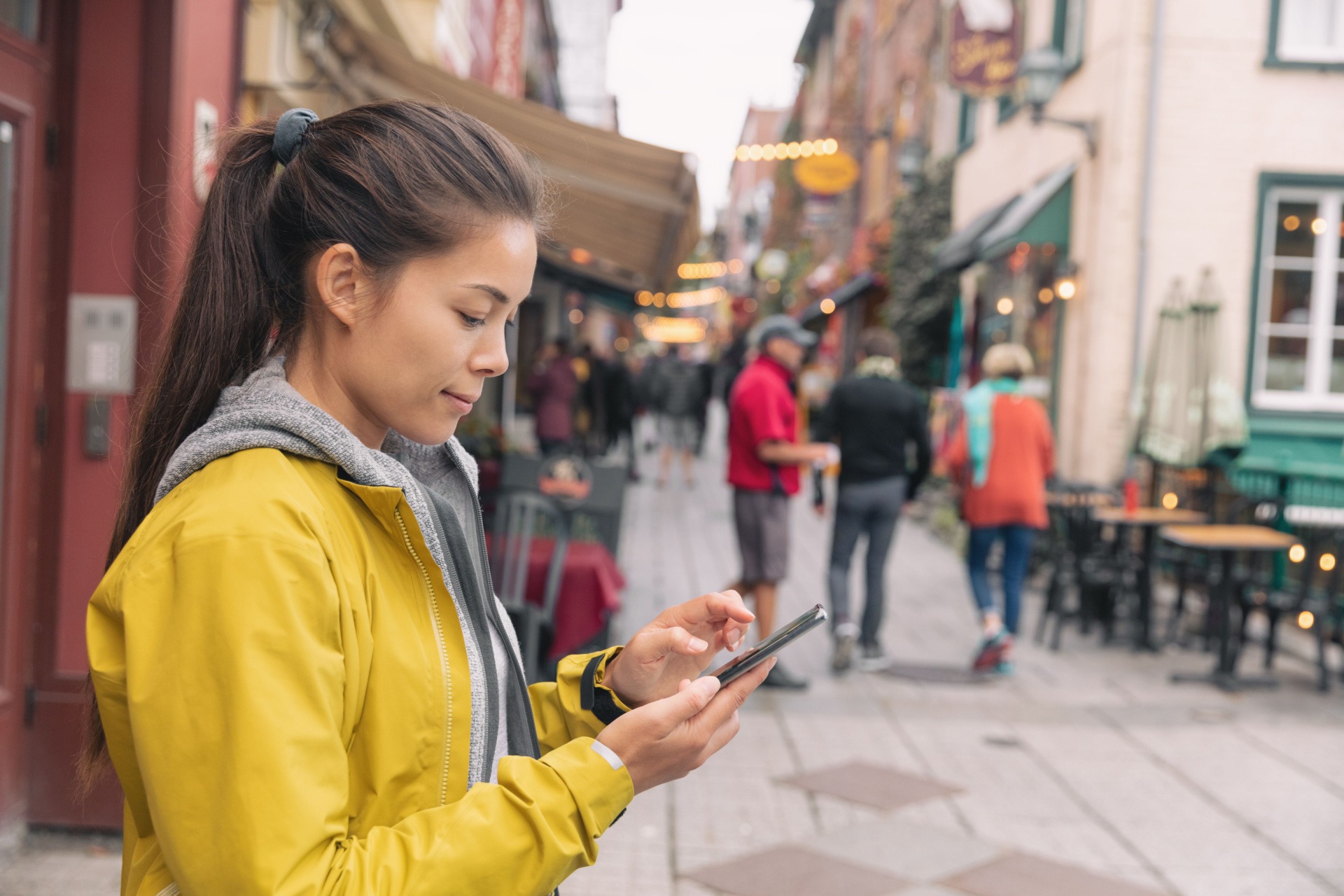 Woman using her phone on a busy sidewalk.