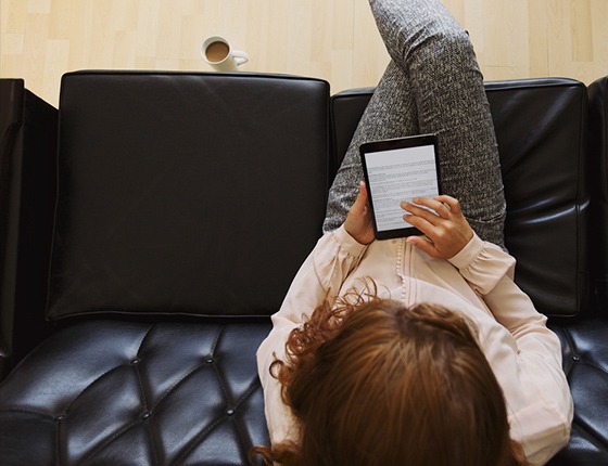Woman sitting on couch searching on her iPad.