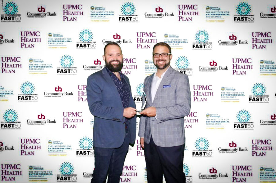 Two man standing together holding award.