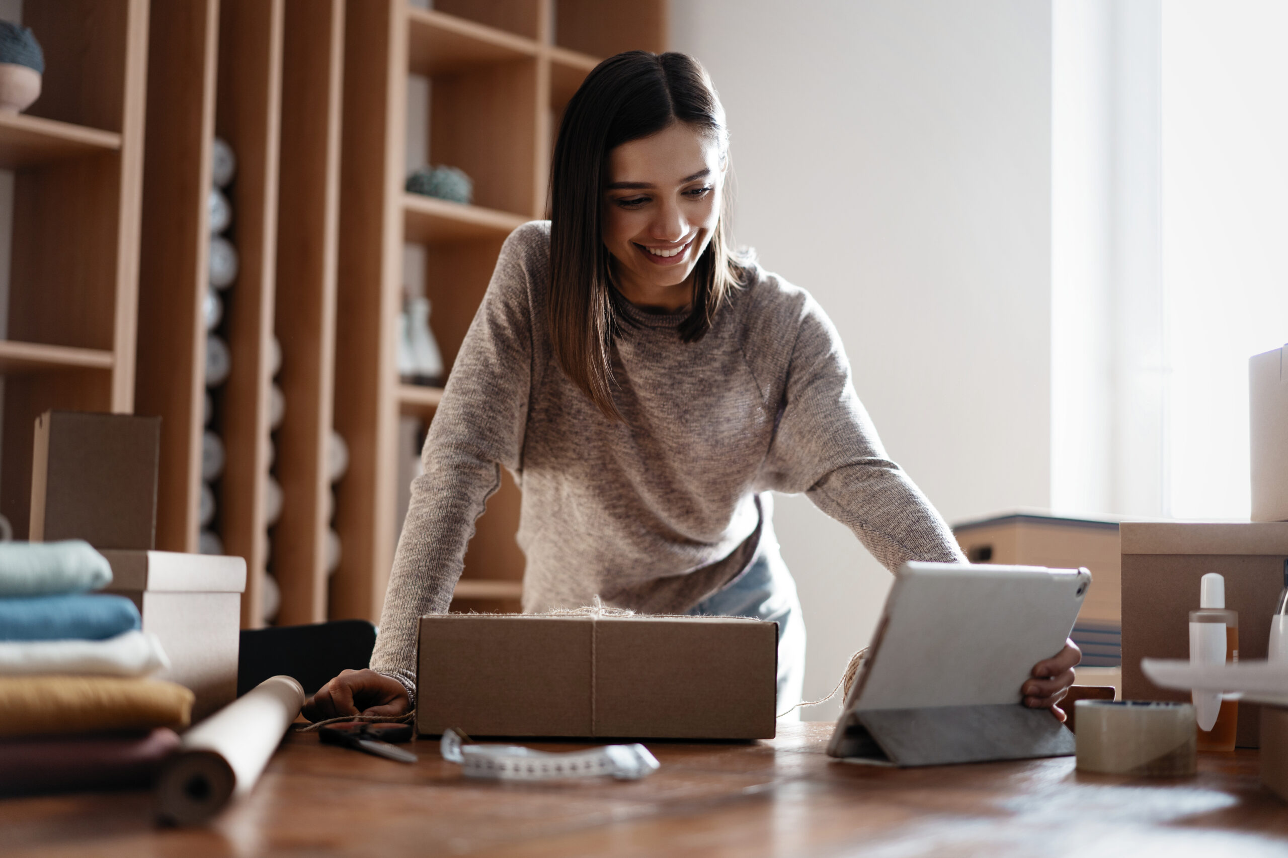 woman leaning over a laptop and tablet