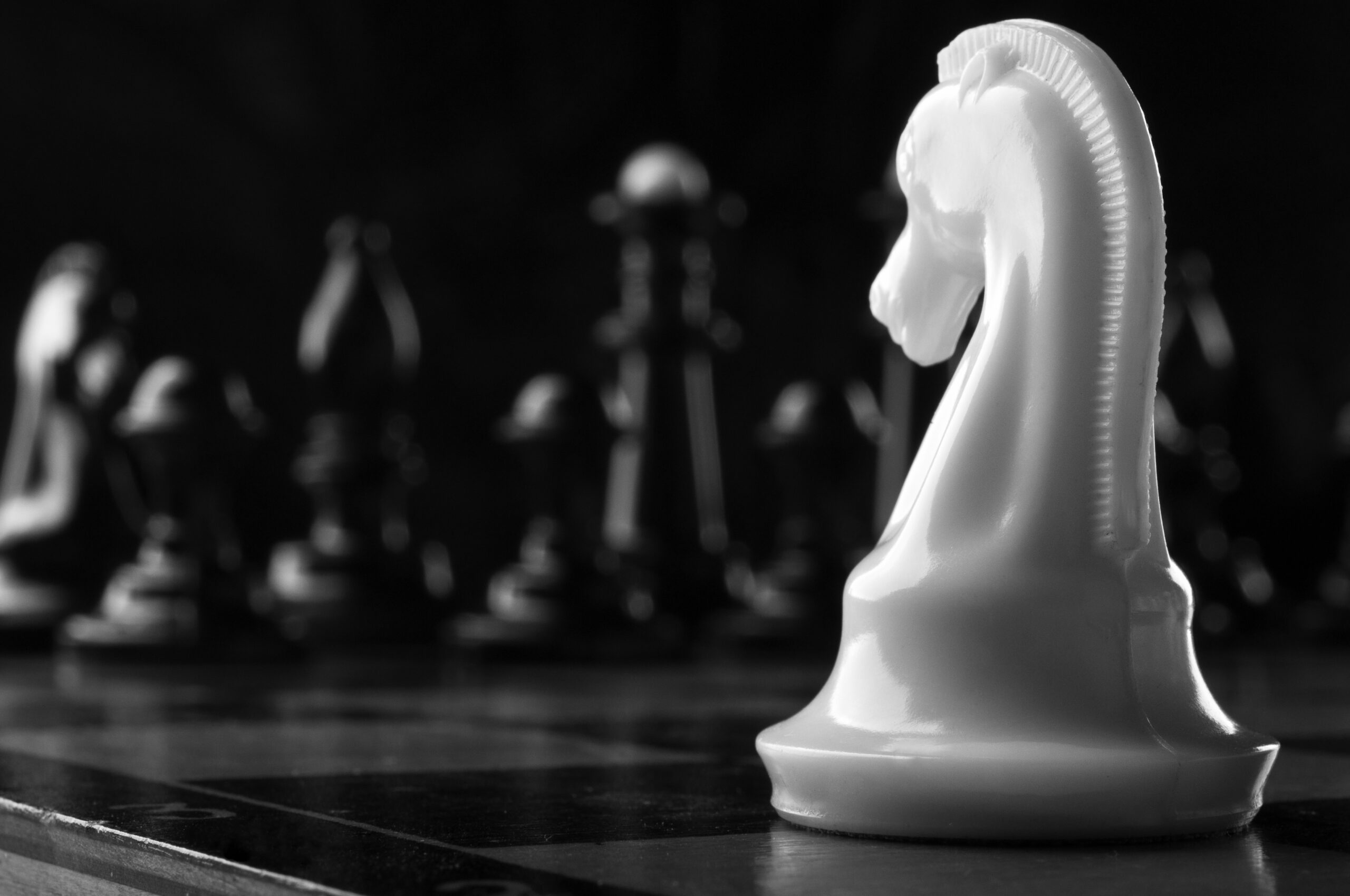 A white knight chess piece facing black chess pieces in a strategic face-off