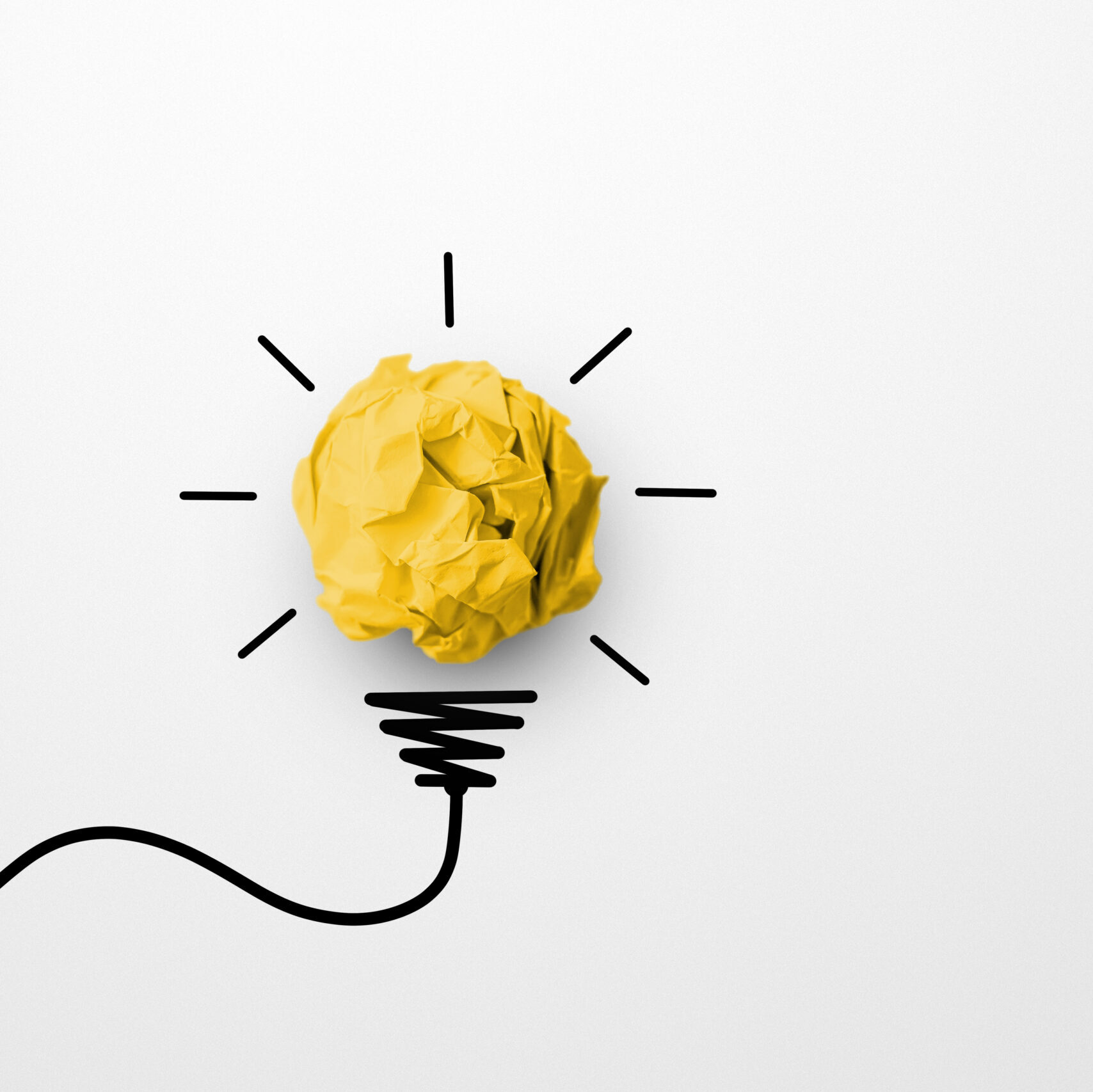 Crumpled yellow paper being drawn into a lightbulb.