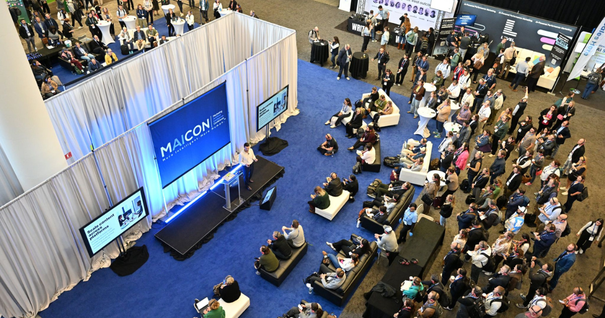 Josh Muskin, Level's VP of Sales, presenting at MAICON 2025, the leading AI marketing conference, speaking to a full session with the Level booth in the background.