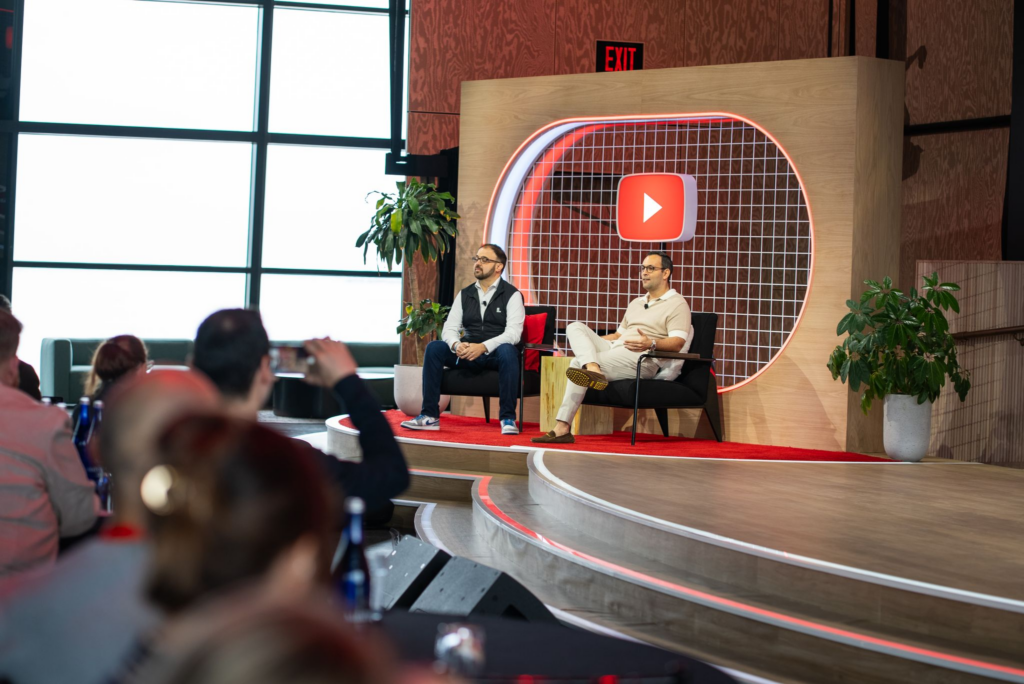 Level Agency CEO, Patrick Patterson, and Google's Head of Agency Chris Marino sit onstage during a fireside discussion at Google’s Brandformance event, framed by a glowing YouTube backdrop and an audience in the foreground.