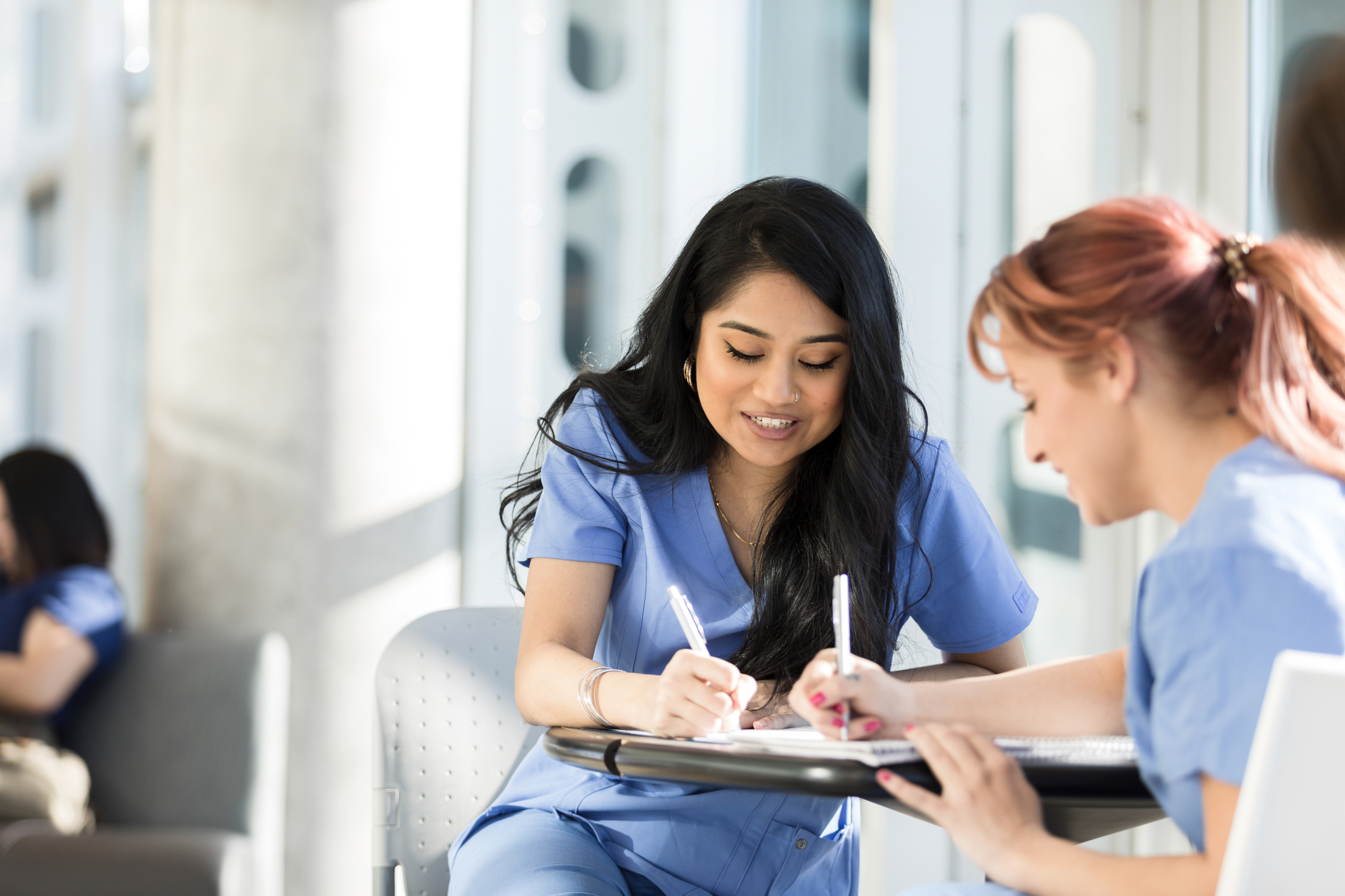 Two career education students in blue scrubs studying together, illustrating the American Career College case study where agentic media buying doubled qualified reach per dollar.