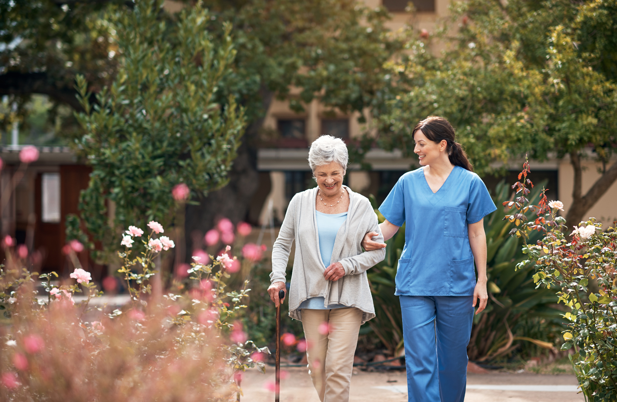 Photo of a caregiver and her patient out for a walk in the garden